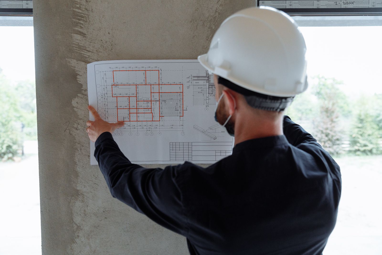 Plano de un proyecto de arquitectura desplegado sobre una mesa con un casco de obra y herramientas de dibujo