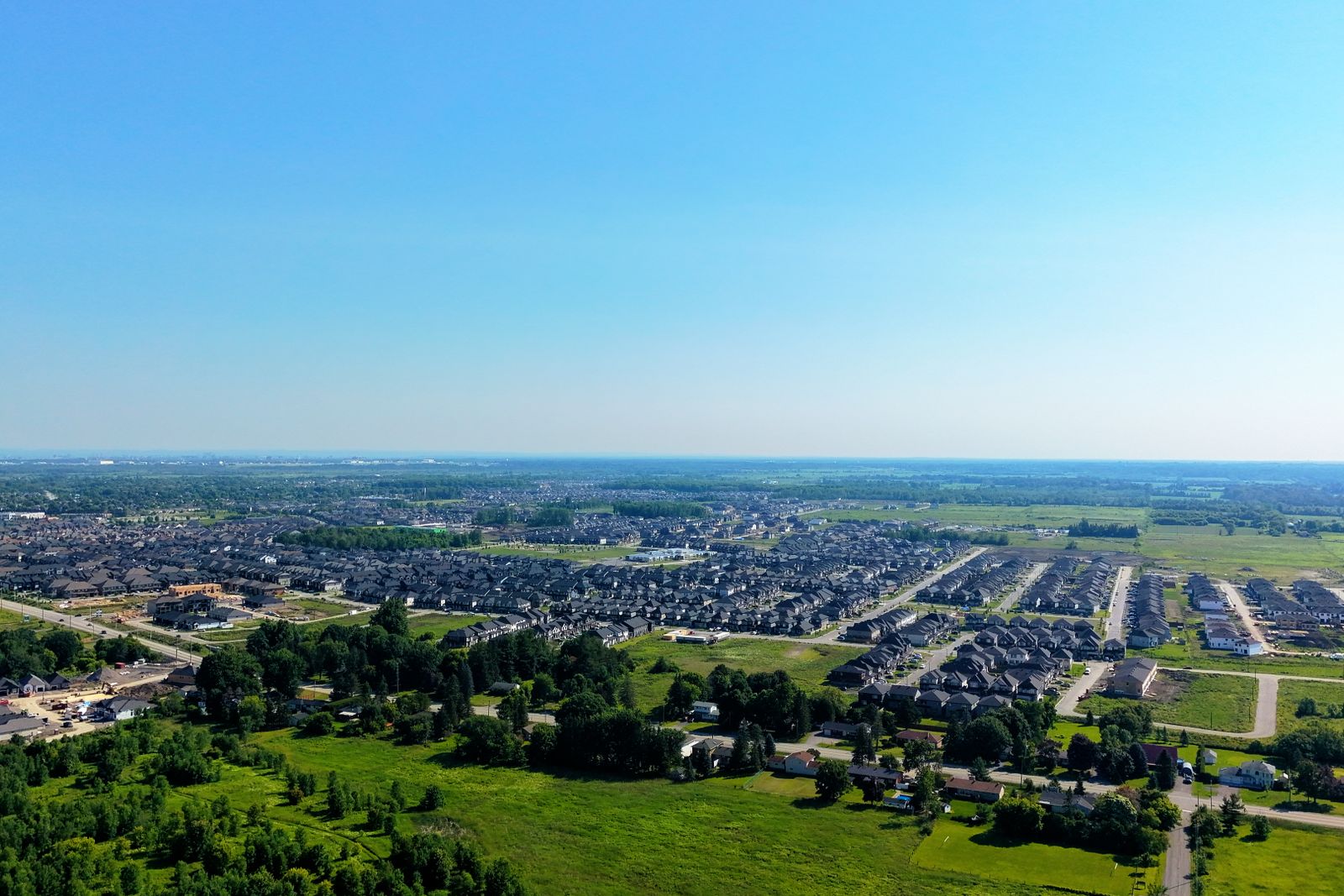 Vista aérea de una zona de expansión urbana con calles recién asfaltadas y parcelas de tierra listas para construir