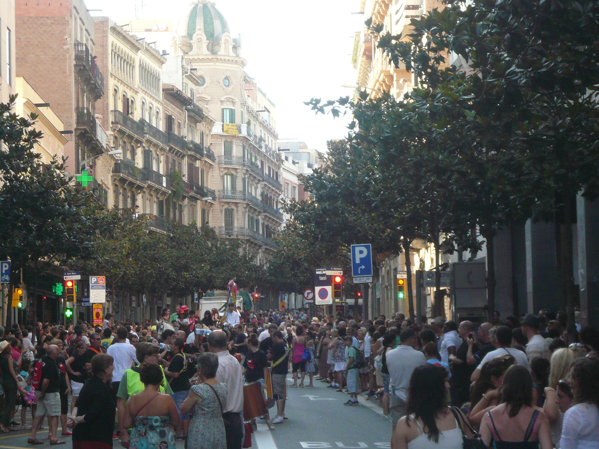 Calle residencial en el barrio de Gràcia con árboles y vecinos paseando