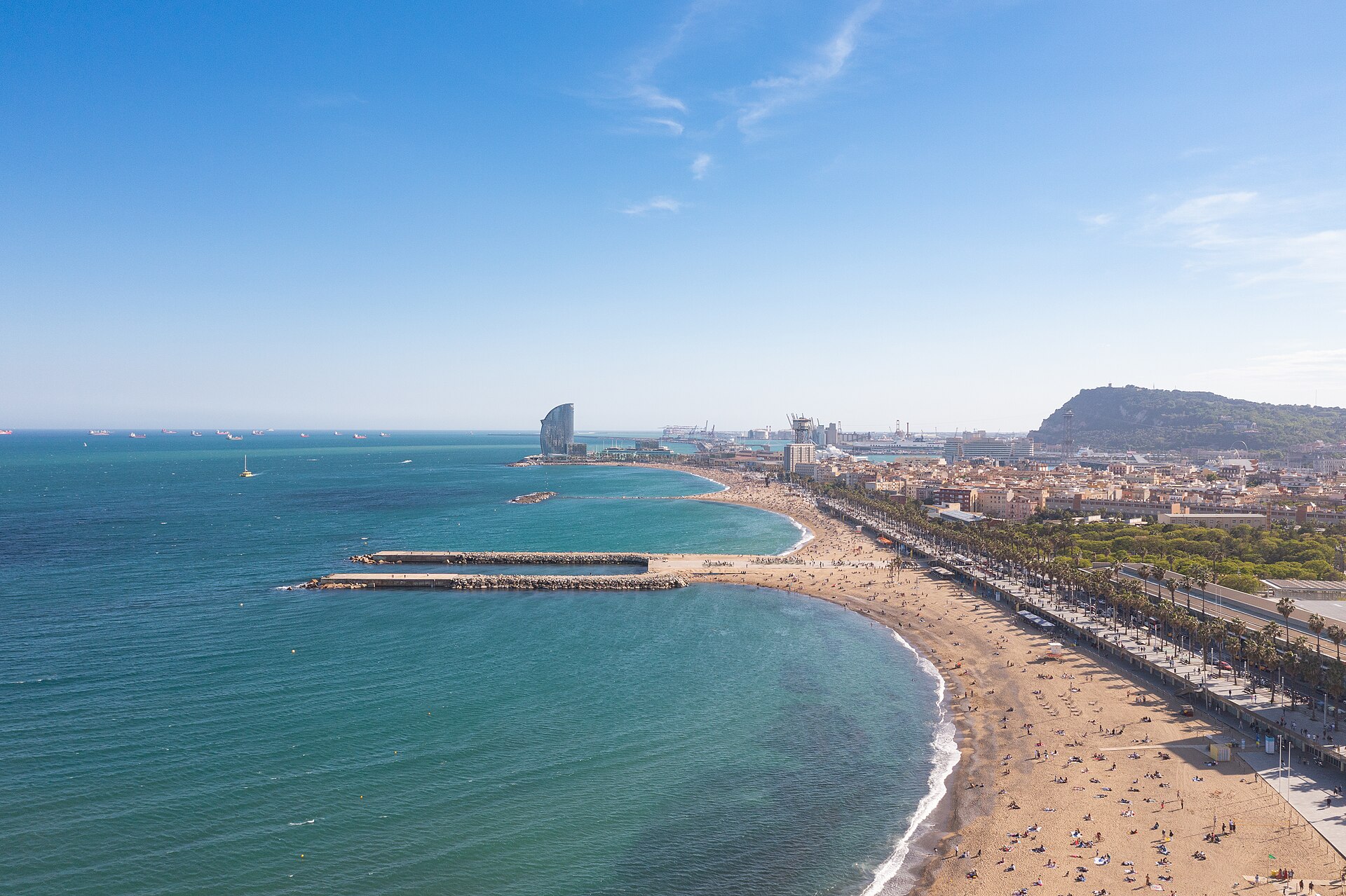 Gente disfrutando del sol y paseando por el paseo marítimo de la playa del Bogatell