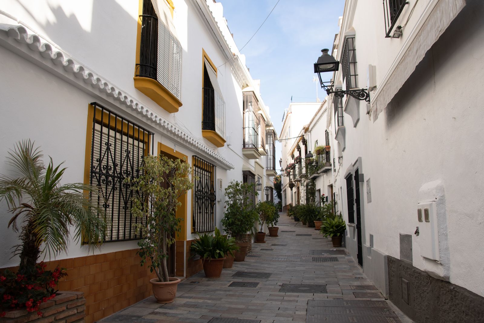 Una calle estrecha y peatonal en el Casco Antiguo de Marbella, con fachadas blancas y macetas colgantes