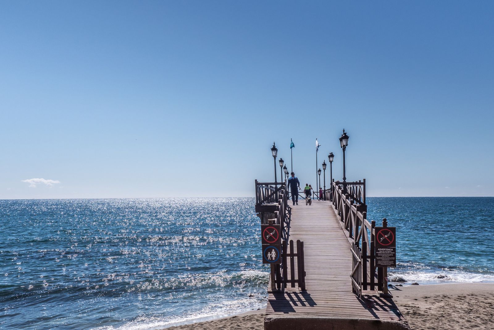 Gente paseando y haciendo deporte en el paseo marítimo pavimentado de Marbella junto a la playa