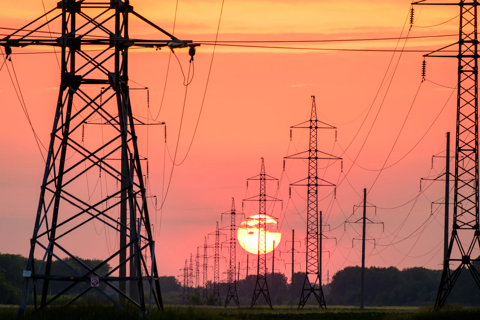 Torre de alta tensión y tuberías industriales al amanecer